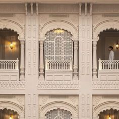 a man is standing on the balcony of a white building with intricate carvings and balconies