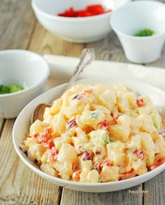 a white bowl filled with macaroni salad next to two bowls