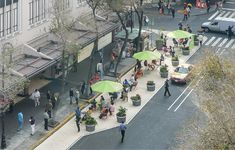 an overhead view of people walking down the street with umbrellas over their heads and cars parked on the side of the road