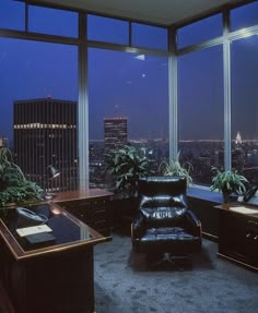 an office with large windows overlooking the city at night, and leather chair in foreground