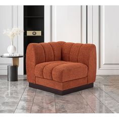 an orange chair sitting on top of a tile floor next to a vase with flowers