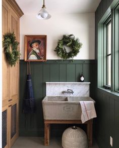 a bathroom with green painted walls and a white sink in the middle, surrounded by greenery