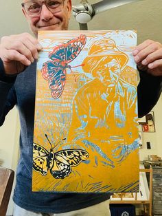 a man holding up a painting with butterflies on it