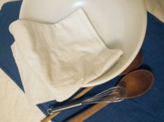 two wooden spoons sitting on top of a white plate next to a blue and white napkin