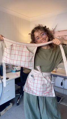 a woman is holding an apron over her shoulder in the room that she works on