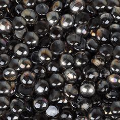 many shiny black beads are shown in this close up photo, with the light reflecting on them