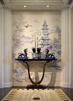 a table with vases and flowers on it in front of a wall