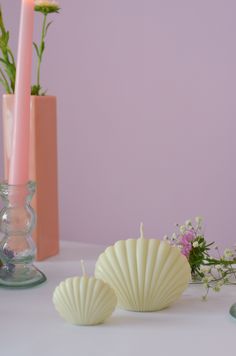 two candles are sitting on a table next to vases with flowers and other items