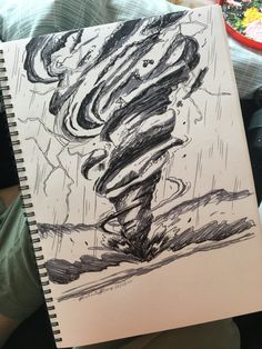 a person holding up a drawing of a tornado