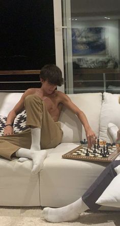 two people sitting on a couch playing chess