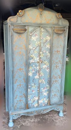 an antique blue armoire with flowers painted on it