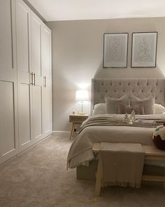 a bed sitting in a bedroom next to two framed pictures on the wall above it