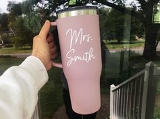 a person holding a pink coffee cup with the words mrs smith on it