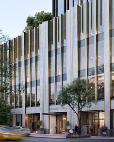 a large building with many windows next to a tree and cars on the street in front of it