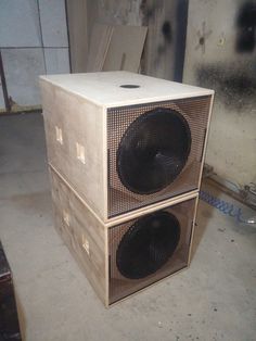 two speakers sitting on top of each other in front of a metal wall and floor