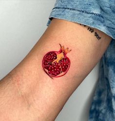 a small pomegranate tattoo on the left arm and wrist is shown in red ink