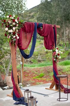 an outdoor wedding setup with red and blue draping, flowers and greenery