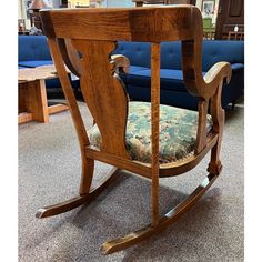 a wooden rocking chair sitting on top of a carpeted floor next to a blue couch