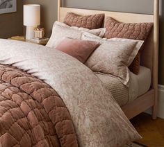 a bed with pink and brown comforters in a bedroom next to a lamp on a table