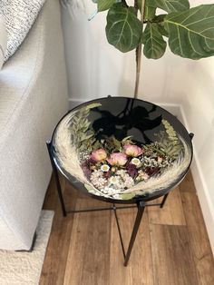 a flower pot sitting on top of a metal stand next to a white couch and wooden floor