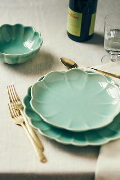 a table set with plates, silverware and wine bottle on it's side