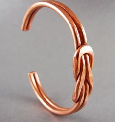 a close up of a metal object on a gray surface with a ring in the shape of a knot