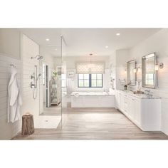 a large white bathroom with two sinks and a walk in shower next to a tub