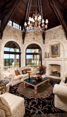 a living room filled with furniture and a chandelier hanging from the ceiling over a fire place