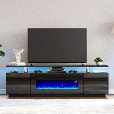 an entertainment center with a television and blue flames on the side, in front of a white rug