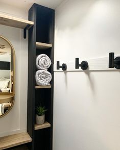 a bathroom with towels on the shelf and a mirror in the corner next to it