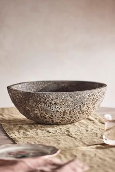 a bowl sitting on top of a table next to a glass bottle and saucer