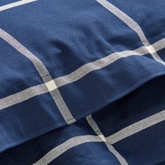 the blue and white checkered blanket is laying on top of the pillowcases