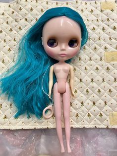 a doll with blue hair laying on top of a quilt