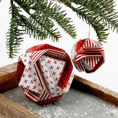 an ornament hanging from a tree branch with snow on the ground below it