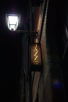 a street light hanging from the side of a brick building in an alleyway at night