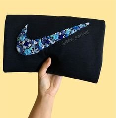 a hand holding up a black bag with blue flowers on it and the nike logo