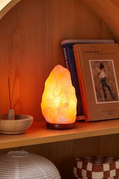 a lamp sitting on top of a wooden shelf next to a bookshelf filled with books