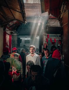 a group of people standing around each other in a room with lights coming from the ceiling