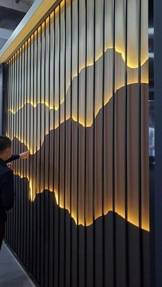 a person standing in front of a wall with mountains on it and lights behind them