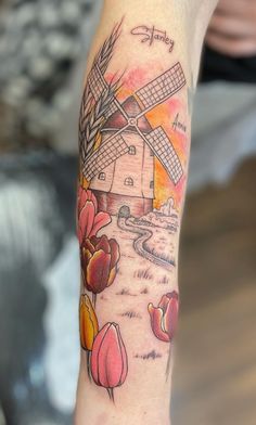 a woman's arm with a windmill and tulips tattoo design on it