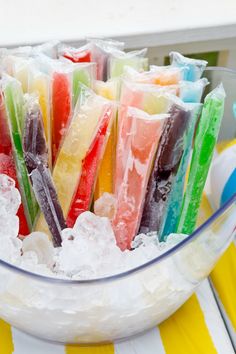 a bowl filled with lots of different colored candies on top of snow covered ground