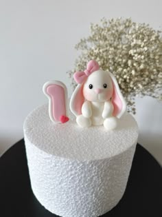 a white cake with a pink bunny sitting on it's top and the number 1