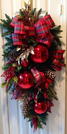 a christmas wreath with red ornaments and pine cones