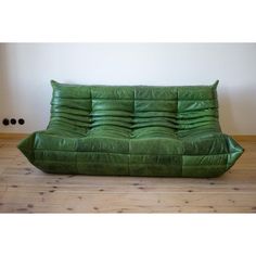 a green leather couch sitting on top of a wooden floor