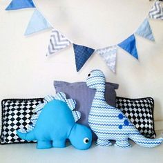 two stuffed animals sitting on pillows in front of a wall with blue and white flags