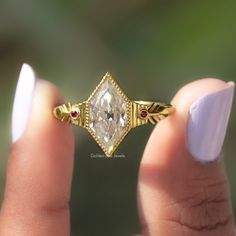 a woman's hand holding a gold ring with a white diamond in the middle