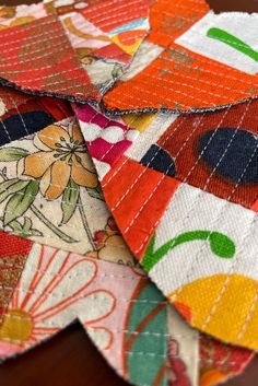 several pieces of colorful fabric sitting on top of a wooden table next to each other