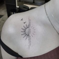 the back of a woman's shoulder with a sun and bird tattoo on it