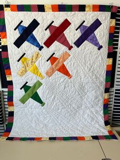 a quilted wall hanging with colorful airplanes on it