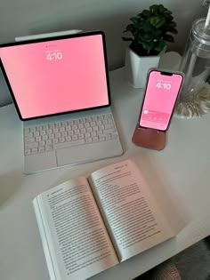 an open laptop computer sitting on top of a desk next to a phone and book